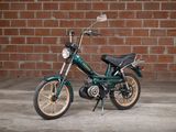 a small green motorcycle parked in front of a brick wall