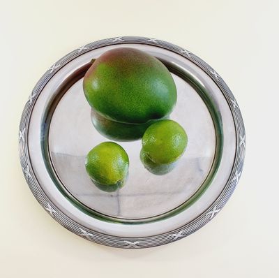three limes on a silver plate on a white table