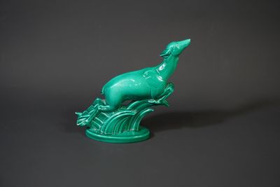 green bird figurine sitting on top of a tree branch
