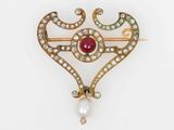 une image représentant une broche en forme de cœur ornée de perles et de pierres précieuses