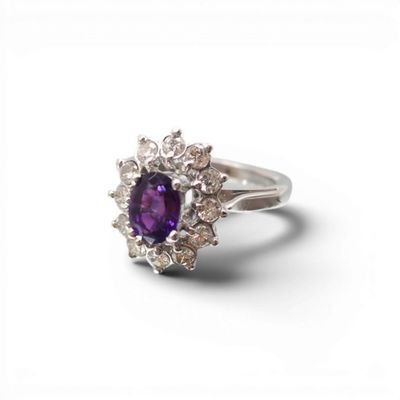 un gros plan d'une bague ornée d'une pierre violette entourée de diamants blancs