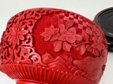 a red vase sitting on a table next to a black object