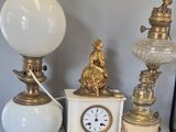 a lot of antique lamps and a clock on a table