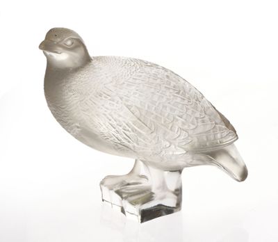 un oiseau en verre posé sur un bloc de verre