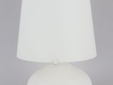 une lampe de table blanche surmontée d'un abat-jour blanc