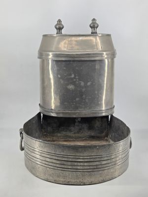 a silver pot sitting on top of a metal pan