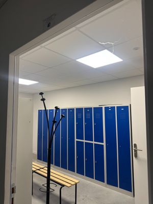 une pièce avec des casiers bleus et un banc à l'intérieur