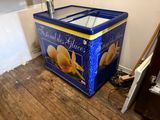 un congélateur à glaces bleu et jaune posé sur un plancher en bois