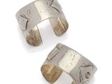 a pair of silver cuff bracelets with engraved designs on them