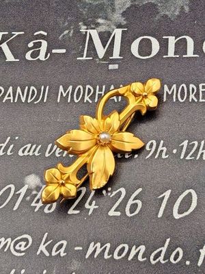 une broche en forme de fleur en or posée sur une plaque