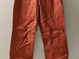 un pantalon orange suspendu à un cintre contre un mur