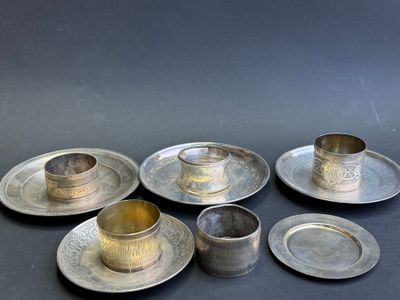 six assiettes et tasses plaquées argent sur un fond noir