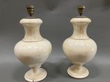 une paire de vases blancs posés l'un sur l'autre sur une surface grise