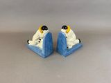 two figurines of a man and a woman sitting on a blue bookends