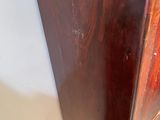 a wooden cabinet in the corner of a room with a door open