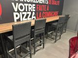 quatre chaises disposées autour d'un bar, avec une enseigne accrochée au mur derrière elles