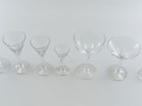 seven empty wine glasses lined up on a white surface