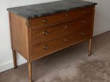a marble top chest of drawers in the corner of a room