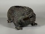 statue en bronze représentant une grenouille assise sur une surface blanche