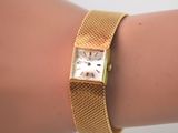 le poignet d'une femme auquel est attachée une montre en or