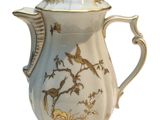 a white and gold coffee pot with birds on it