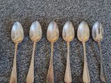 six silver spoons are lined up in a row on a carpet