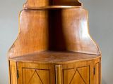 an old wooden corner cabinet with two doors and a shelf