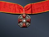 a close up of a red ribbon with a cross on it