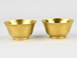 a pair of brass cups on a white background