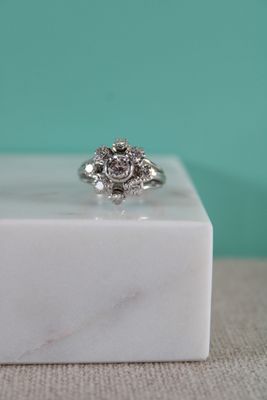 un gros plan d'une bague en diamant posée sur un bloc de marbre