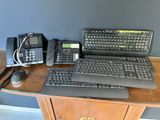 un bureau sur lequel se trouvent un ordinateur portable, un clavier, un téléphone et un poste téléphonique