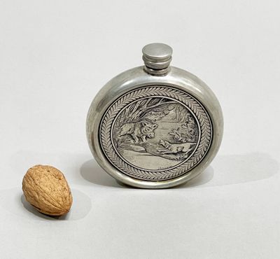 a silver flask with a picture of a man and a dog on it