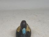 a small black and gold duck sitting on a white surface