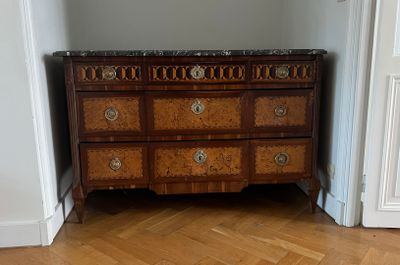 a dresser in the corner of a room with a mirror above it