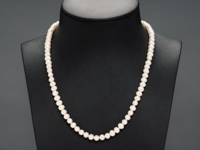 un collier de perles blanches sur un mannequin avec un fermoir en or