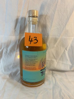 a bottle of liquor sitting on a bed with a label on it