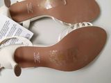 pair of women ' s white shoes on a white surface with a price tag