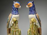 une paire de perroquets en céramique bleue et blanche, perchés sur une souche d'arbre