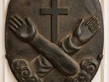 une image représentant une plaque sur laquelle figurent une croix et des mains
