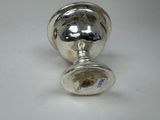 a silver object on a table with a white background