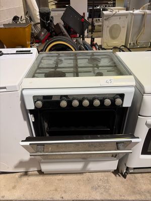une cuisinière blanche avec un plan de cuisson en verre, placée à côté d'une machine à laver