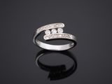 une bague en or blanc et diamants posée sur une surface noire