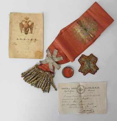 un vieux document orné d'un ruban rouge et d'autres objets posés sur une table