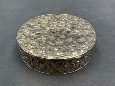 une boîte en argent finement décorée de fleurs, posée sur une table