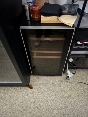 un réfrigérateur noir avec une porte vitrée et une étagère noire