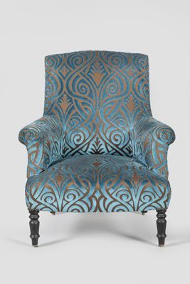 an upholstered chair with a blue and brown patterned upholstered back