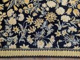 a black rug with yellow flowers on it on a wooden floor