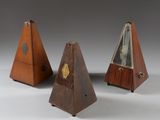 trois pyramides en bois, chacune surmontée d'une horloge