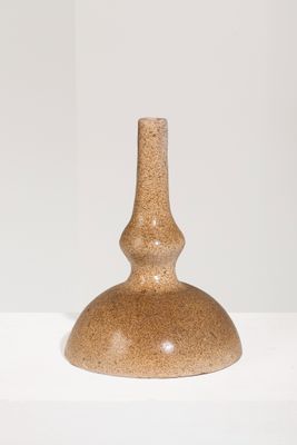 un vase marron posé sur une étagère blanche, sur fond blanc