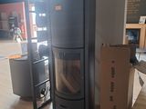 un poêle noir posé au milieu d'une pièce, à côté de cartons
